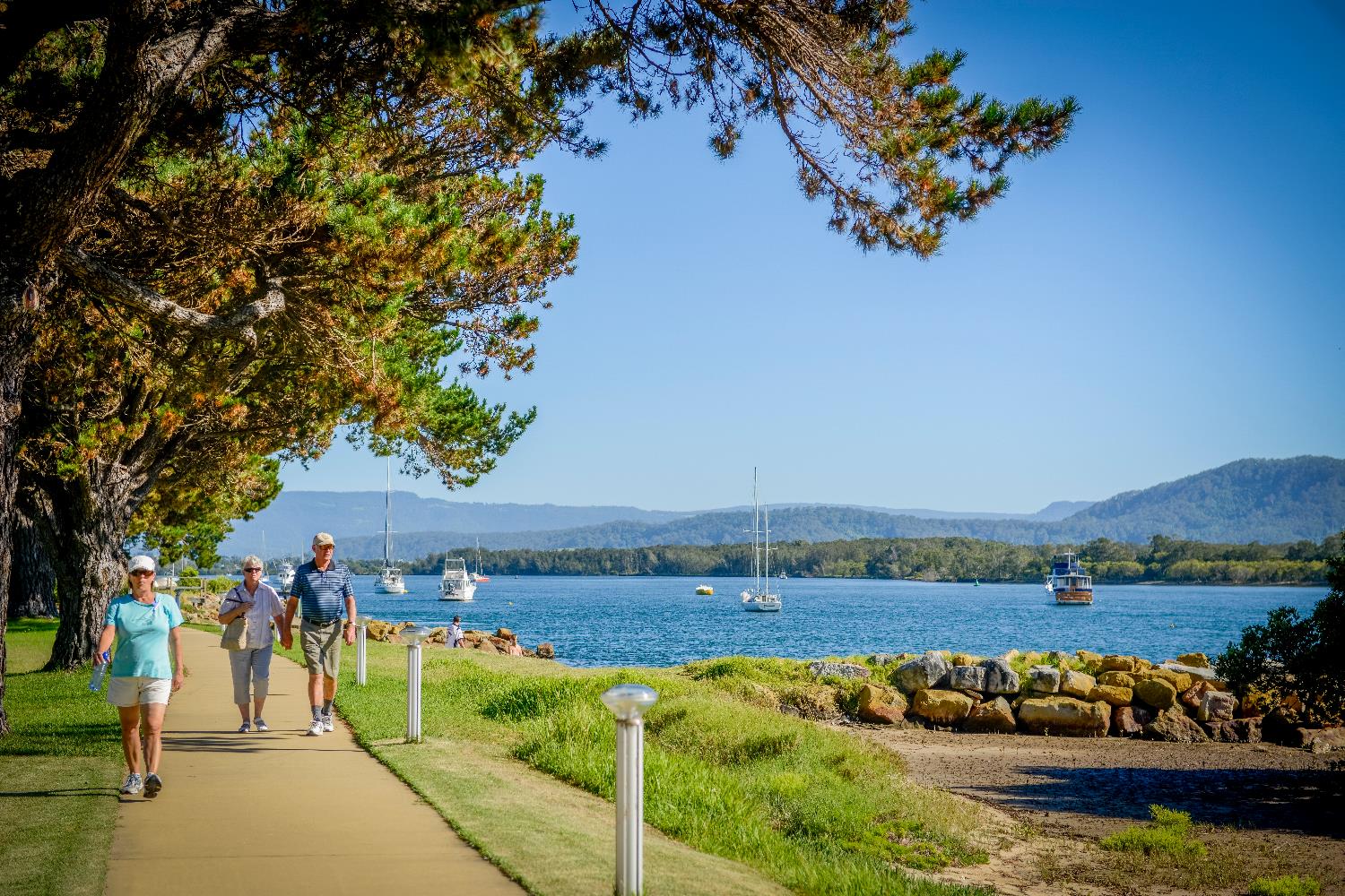 People walking along the footpath at the Foreshore Reserve, with a view of the water in the background.
