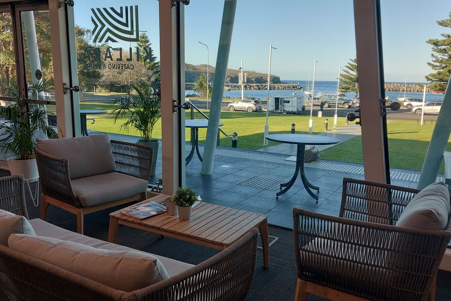 View of harbour from inside the café, with a cane lounge setting next to the windows.