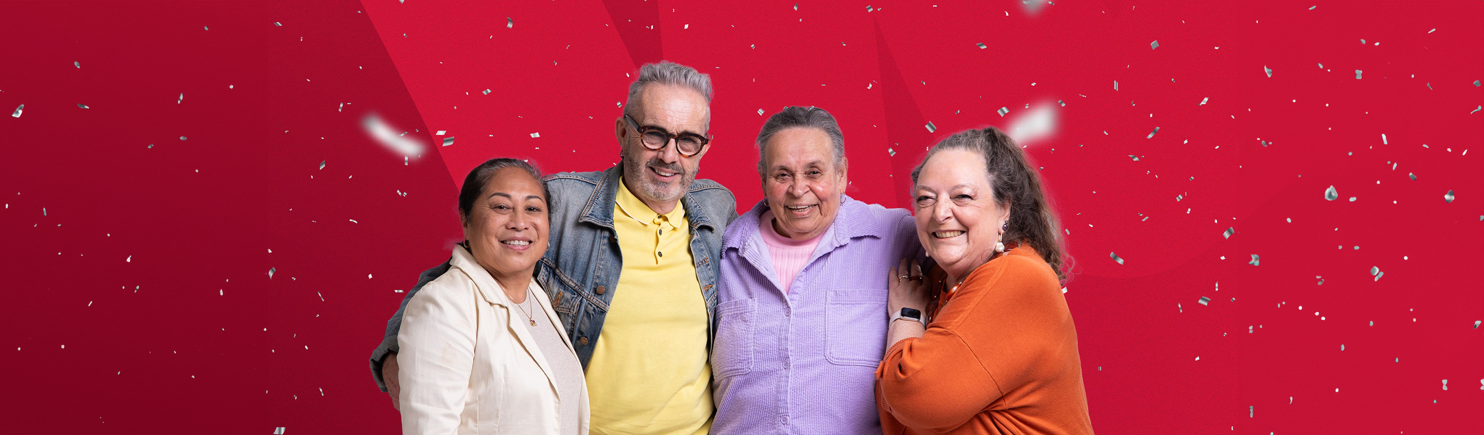 Photo of four australian seniors smiling at the camera while silver confetti falls around them