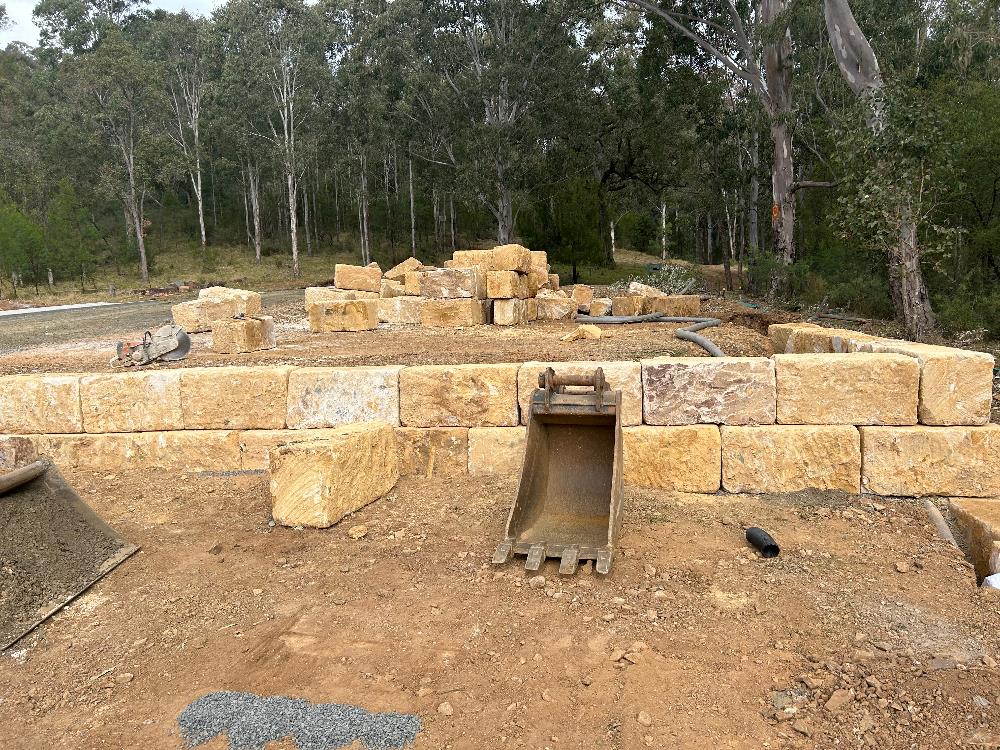 Half-constructed retaining wall of large sandstone blocks