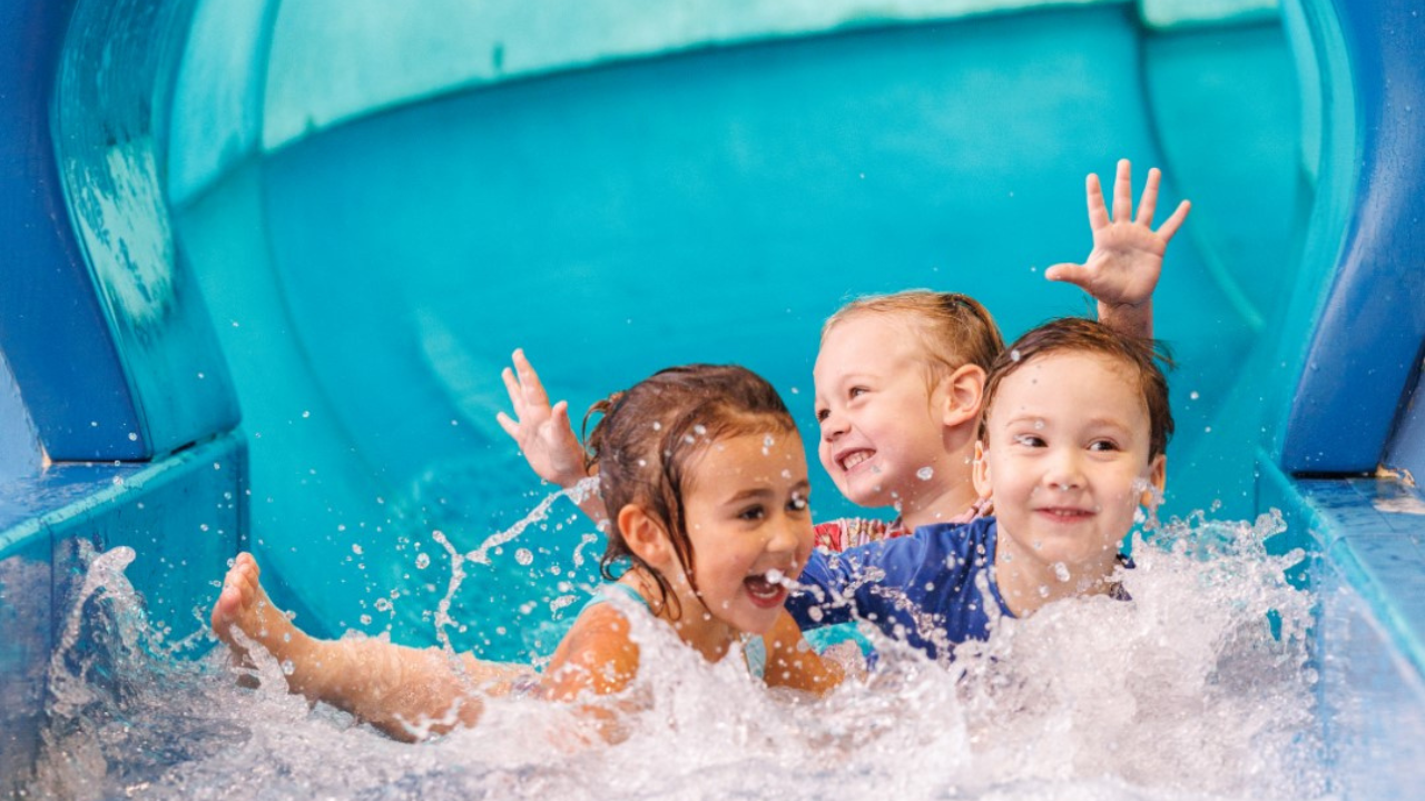 A photo of a child coming down a water filled slide.