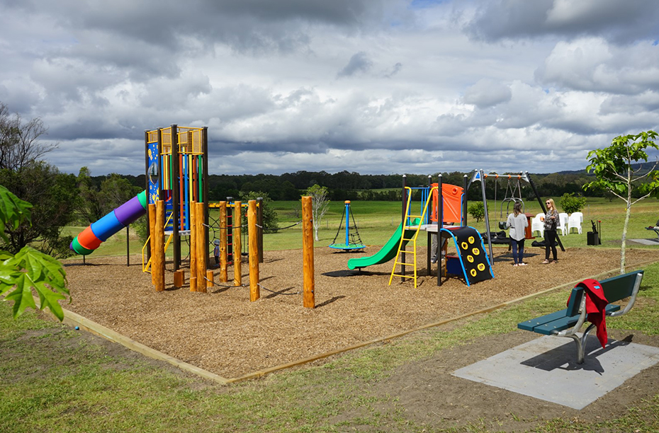 Two adults in conversation among playground equipment