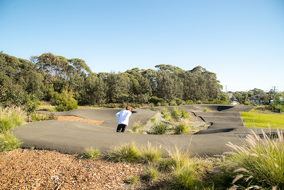 Teenager in white shirt skating around bank on pump track